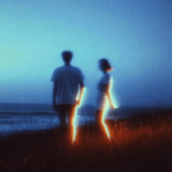 Two silhouettes on a beach at dusk