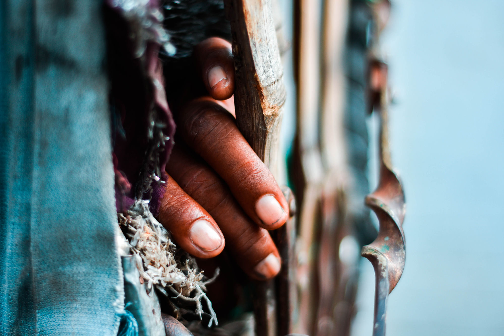 Hand gripping a cart's wooden frame, Patna market